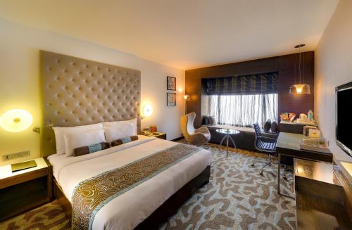 una camera d'albergo con un grande letto e una TV di The Pride Hotel, Bangalore a Bangalore