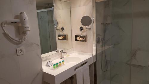 a bathroom with a sink and a shower with a mirror at Senator Barajas in Madrid