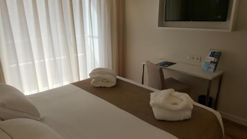 a room with a bed and a table and a television at Senator Barajas in Madrid