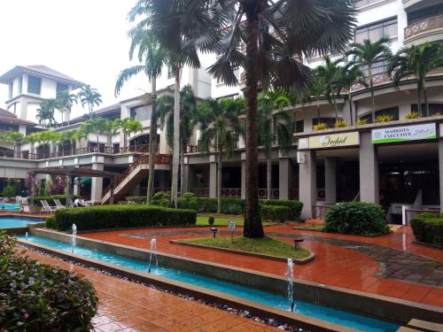 a resort with palm trees in front of a building at Costa Mahkota (Family Homestay) @ Mahkota Melaka in Melaka