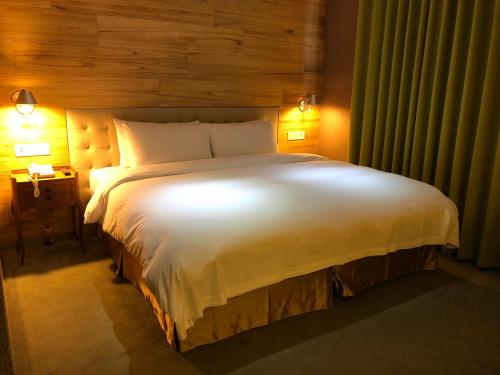 a bedroom with a large white bed with two lights at Inhouse Hotel Taichung in Taichung