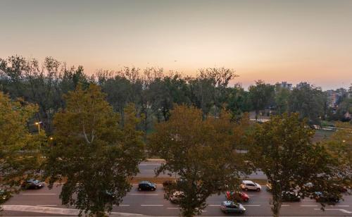 a parking lot with cars in a parking lot with trees at Park Apartment in Novi Sad