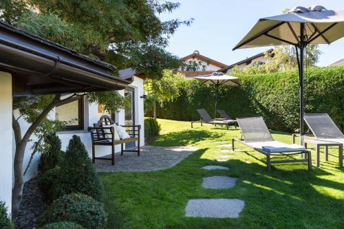 a patio with lawn chairs and an umbrella at Hotel MAYR in Castelrotto