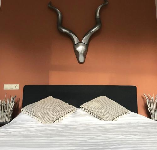 een slaapkamer met een bed met 2 kussens en een antilope hoofdeinde bij De Pelgrimsplaats in Leiden