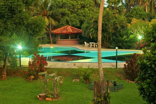 a swimming pool with a gazebo in a garden at Villa Ranmenika in Ahungalla