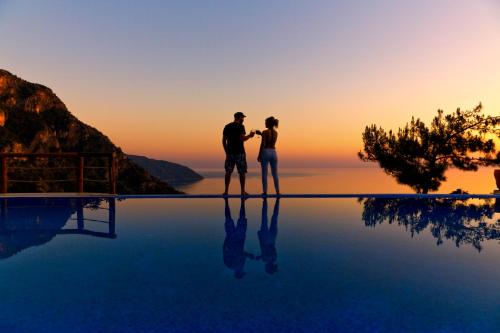 a man and a woman standing on the edge of a pool at Lissiya Hotel in Faralya