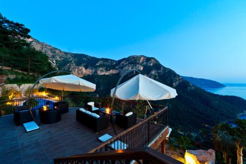 a patio with chairs and umbrellas overlooking the ocean at Lissiya Hotel in Faralya