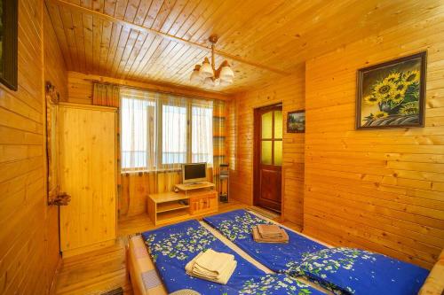 a bedroom with a blue bed in a wooden room at Villa U Tsymbora in Sinyak