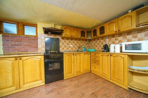 a kitchen with wooden cabinets and a black stove top oven at Villa U Tsymbora in Sinyak