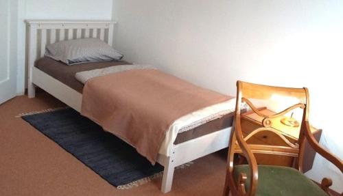 - une petite chambre avec un lit et une chaise dans l'établissement Ferienwohnung Hofgarten, à Ansbach