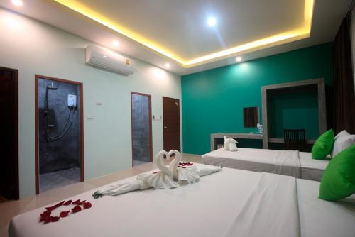 a bedroom with two beds with white sheets and a green wall at The Aireen Hotel in Ao Nang Beach