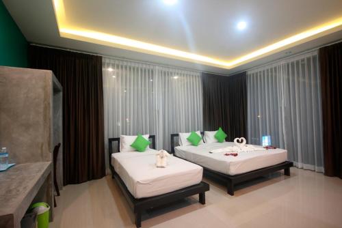 a hotel room with two beds with green and white pillows at The Aireen Hotel in Ao Nang Beach