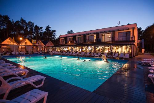 a swimming pool with people in the water at night at Holiday Park & Resort Grzybowo in Grzybowo