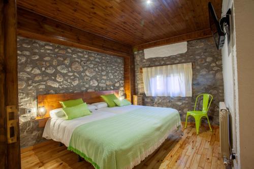 a bedroom with a bed and a stone wall at Hotel Cal Rei de Talló in Bellver de Cerdanya 