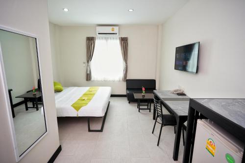 バンコクにあるSabai Place Donmueang Airportのベッド、テーブル、椅子が備わる小さな客室です。