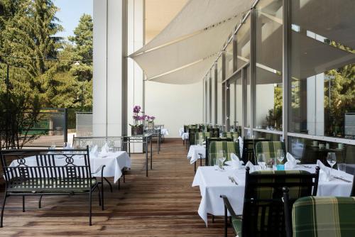 a restaurant with white tables and chairs on a wooden floor at Wyndham Grand Salzburg Conference Centre in Salzburg