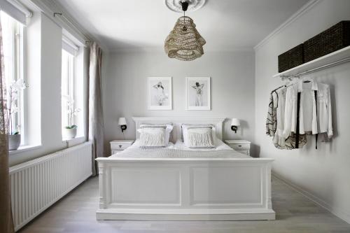 a white bedroom with a white bed and a chandelier at WOW, Föreningsgatan 9 in Gothenburg