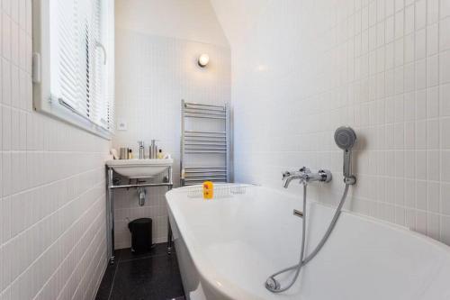 une salle de bain blanche avec une baignoire et un lavabo dans l'établissement Joie Paris Opéra - Gare St Lazare, à Paris