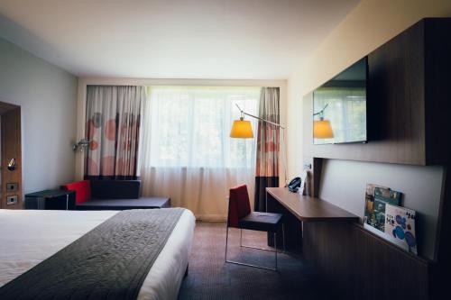 a hotel room with a bed and a desk at Novotel Coventry in Coventry