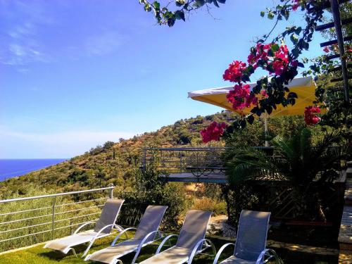 a group of chairs and an umbrella and the ocean at Dio Guesthouses in Leonidion