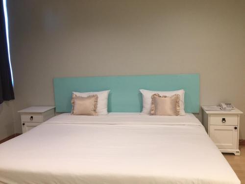 a large bed with a blue headboard and pillows at Rattana View in Phitsanulok