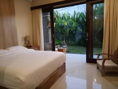 a bedroom with a bed and a sliding glass door at Guest House Reisya in Nusa Dua