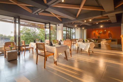 a restaurant with white tables and chairs and windows at Akhyana Village in Jimbaran