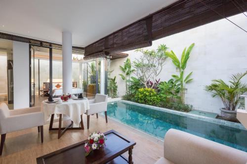 a living room with a pool and a table and chairs at Akhyana Village in Jimbaran