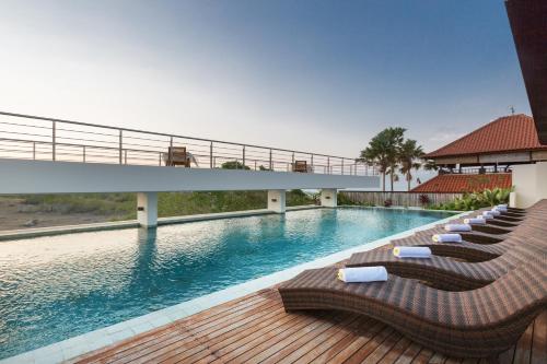 a swimming pool with lounge chairs and a bridge at Akhyana Village in Jimbaran