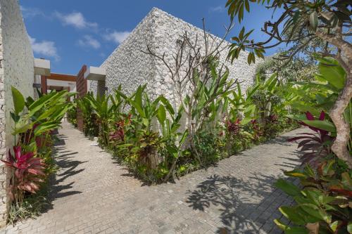 a brick walkway next to a white building with plants at Akhyana Village in Jimbaran