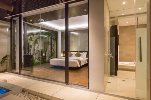 a bedroom with a bed in a room with glass walls at Akhyana Village in Jimbaran
