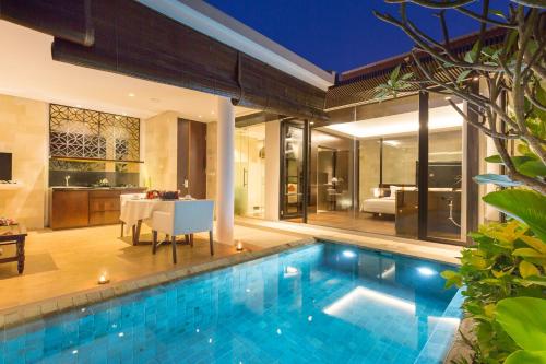 a swimming pool in a villa with a dining room at Akhyana Village in Jimbaran