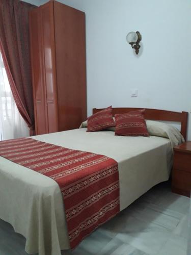 a bedroom with a large bed with red pillows at Hostal Centro Sol in Cádiz