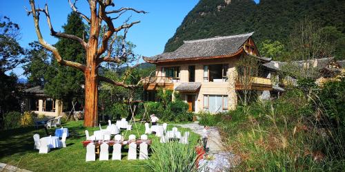 a yard with white chairs and a house at Evergreen Retreat-walk to National Forest Park, free pick up service in Zhangjiajie