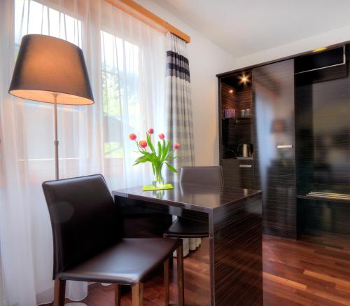 a dining room table with a lamp and a vase of flowers at Hotel Brienzersee in Ringgenberg