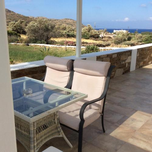 a chair and a glass table on a balcony with the ocean at Ostria Village in Mylopotas