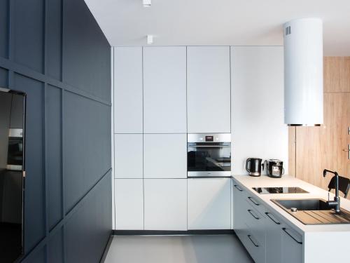 a kitchen with white cabinets and a black refrigerator at Ataner Apartamenty in Koszalin