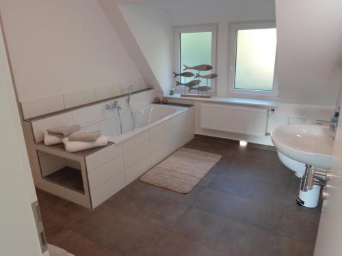 ein weißes Badezimmer mit einer Badewanne und einem Waschbecken in der Unterkunft Ferienwohnung Dawe in Göttingen