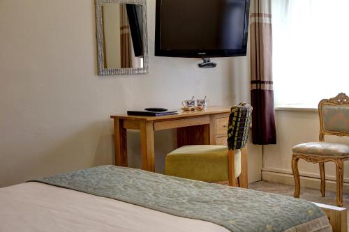 a bedroom with a bed, chair, desk and television at Best Western Walworth Castle Hotel in Darlington