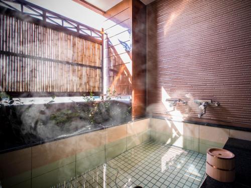 a bathroom with a tub and a sink and a window at Dogo Onsen Yachiyo 道後温泉八千代 in Matsuyama