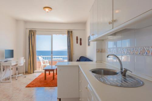 een keuken met een wastafel en uitzicht op de oceaan bij Bahia suite in Puerto de Santiago