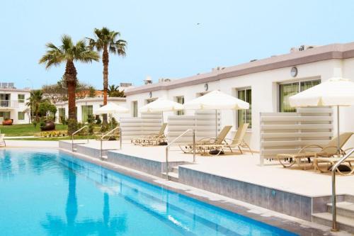 a pool at a hotel with chairs and umbrellas at Sunprime Ayia Napa Suites - Adults Only in Ayia Napa