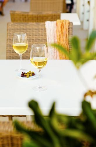 two glasses of white wine sitting on a table at Sunprime Ayia Napa Suites - Adults Only in Ayia Napa