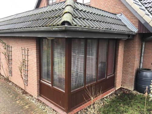 a conservatory with a metal roof on a brick house at Smans Fewo in Neustadt in Holstein