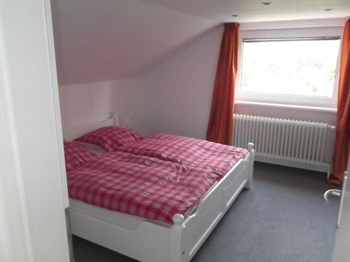 um quarto com uma cama com um cobertor xadrez vermelho em Vogler Lothar em Neustadt in Holstein