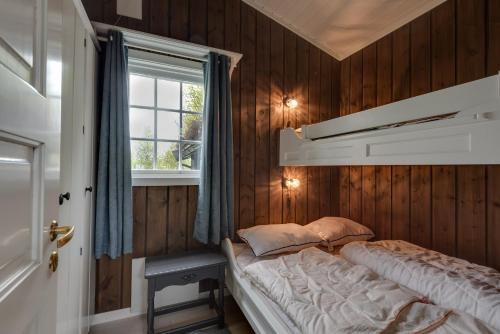 1 dormitorio con paredes de madera y 1 cama con ventana en Bitigrenda F en Beitostøl