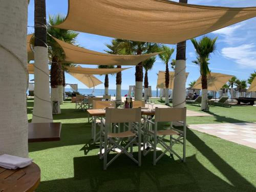 a table and chairs under a canopy with palm trees at Los Flamingos Tee 6 in Estepona