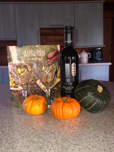 a bottle of wine sitting on a counter next to pumpkins at Log home village in Ulverston