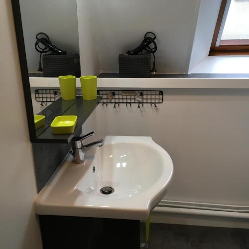 - un lavabo avec 2 tasses jaunes et un miroir dans l'établissement le 2018, à Cancale