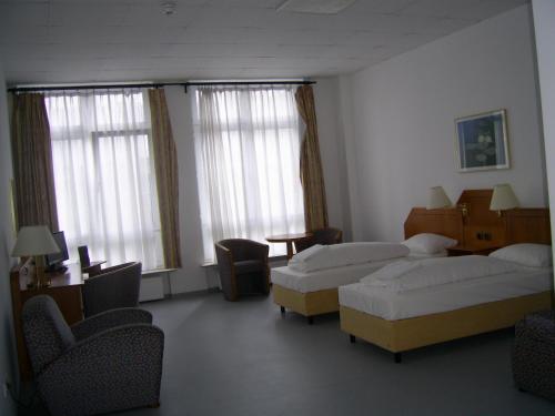 a room with three beds and chairs and windows at Willy Hotel Frankfurt in Frankfurt/Main
